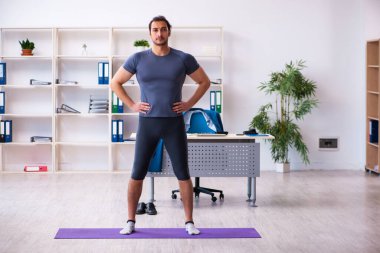 Genç yakışıklı çalışan ofiste spor egzersizleri yapıyor.