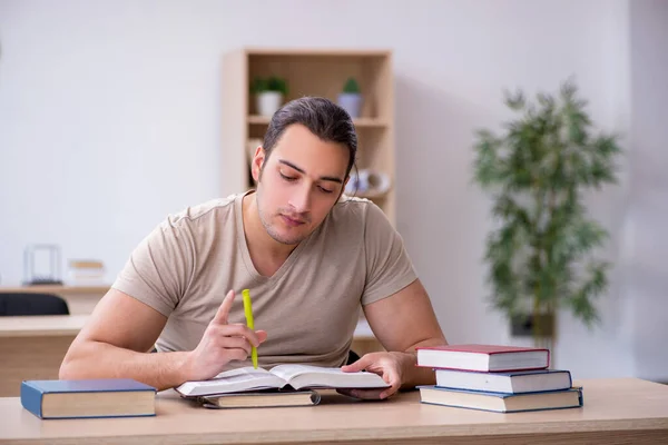 Joven estudiante masculino preparándose para los exámenes en la biblioteca — Foto de Stock