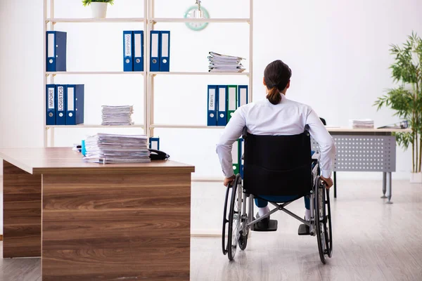 Молодой работник после аварии в инвалидной коляске на рабочем месте — стоковое фото