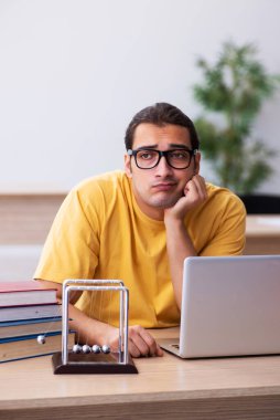 Genç erkek öğrenci fiziği sınavlara hazırlanıyor.