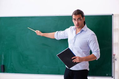 Tahtanın önündeki genç erkek öğretmen.