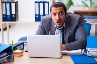 Genç bir erkek çalışan ve ofiste çok fazla iş var.