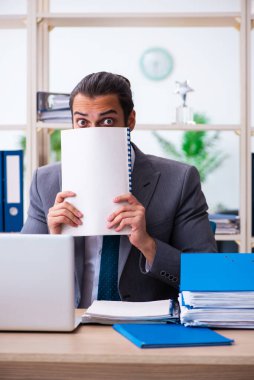 Genç bir erkek çalışan ve ofiste çok fazla iş var.