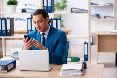 Genç yakışıklı çalışan ofiste oturuyor.