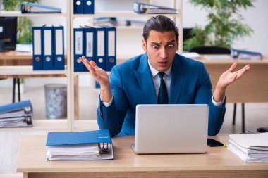 Genç yakışıklı çalışan ofiste oturuyor.