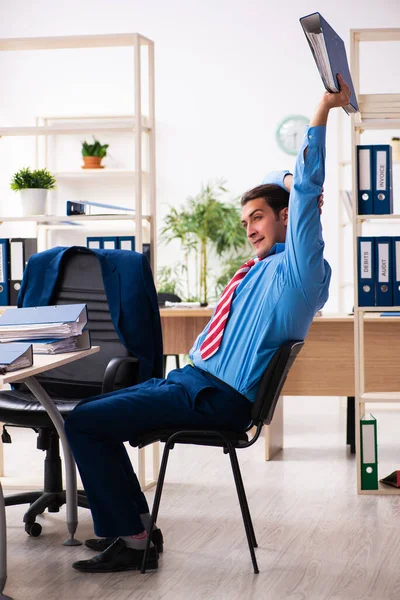 Joven empleado masculino haciendo ejercicios deportivos en el lugar de trabajo —  Fotos de Stock