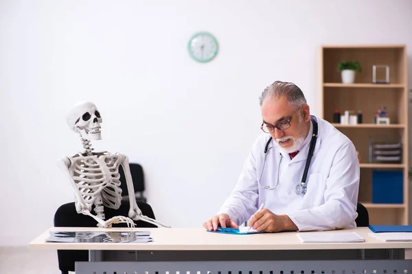 Velho médico masculino e paciente esqueleto na clínica — Fotografia de Stock