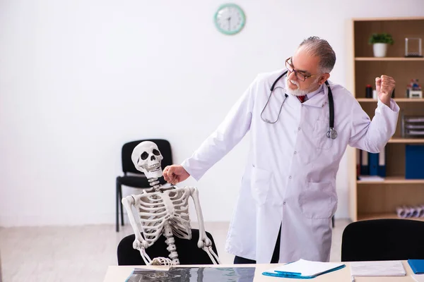 Velho médico masculino e paciente esqueleto na clínica — Fotografia de Stock