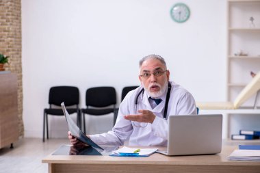 Klinikte çalışan yaşlı erkek doktor.