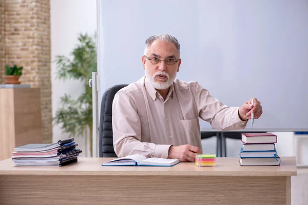 Velho professor sentado na sala de aula — Fotografia de Stock