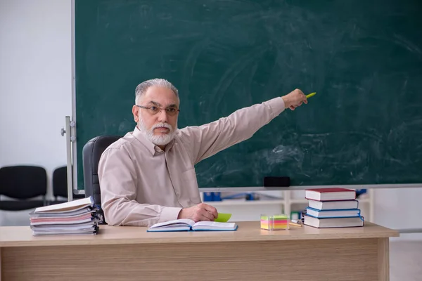 Starý muž učitel sedí ve třídě — Stock fotografie