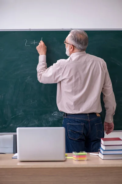 Gammal manlig lärare sitter i klassrummet — Stockfoto