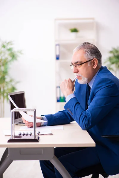 Oude mannelijke werknemer zakenman en meditatie ballen op het bureau — Stockfoto