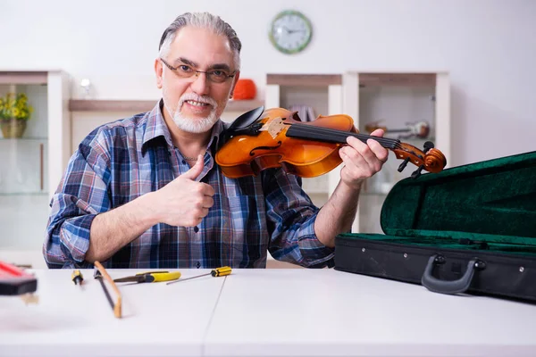 Réparateur masculin senior réparant des instruments de musique à la maison — Photo