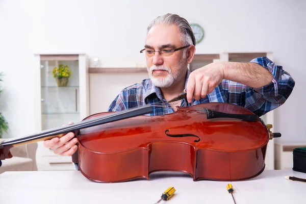 Hombre mayor reparador reparando instrumentos musicales en casa — Foto de Stock