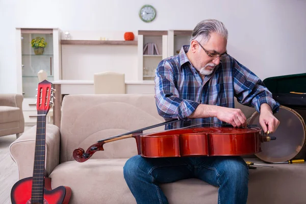 Reparador sênior do sexo masculino reparando instrumentos musicais em casa — Fotografia de Stock