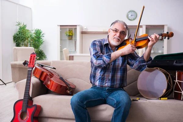 Seniorchef repariert Musikinstrumente zu Hause — Stockfoto