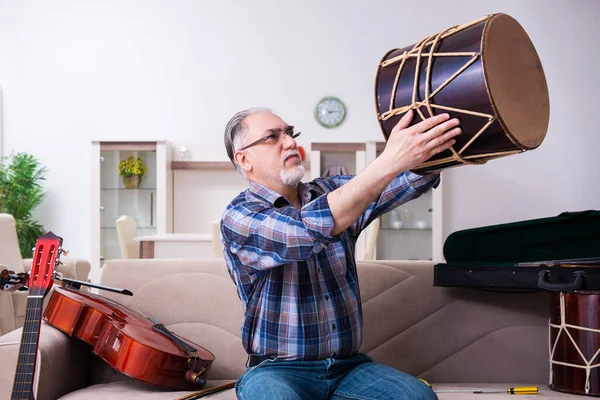 Starší opravář mužského pohlaví opravuje doma hudební nástroje — Stock fotografie