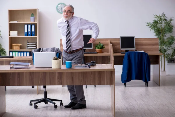 Oude mannelijke werknemer die lijdt aan radiculitis op de werkplek — Stockfoto