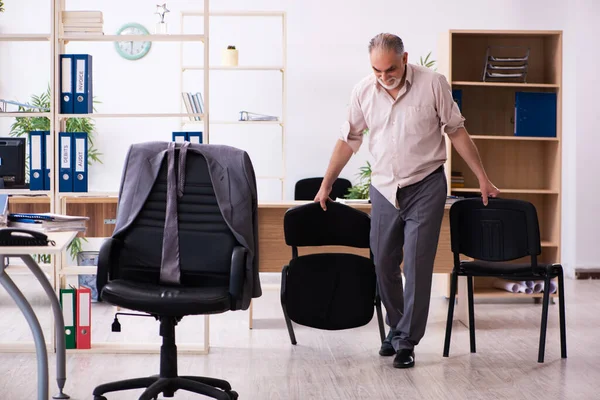 Velho funcionário do sexo masculino fazendo exercícios físicos no local de trabalho — Fotografia de Stock