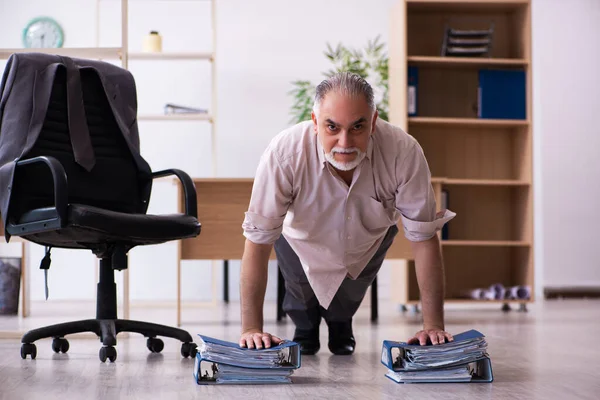 Vecchio dipendente maschio che fa esercizi fisici sul posto di lavoro — Foto Stock