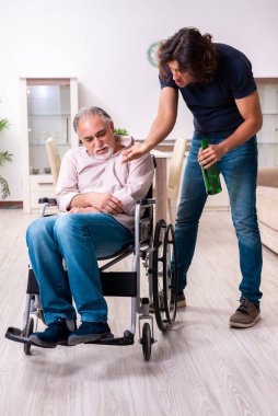 Tekerlekli sandalyedeki yaşlı adam ve genç kötü bakıcı.