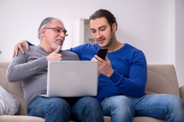 Baba oğul kanepede bilgisayar başında oturuyor.