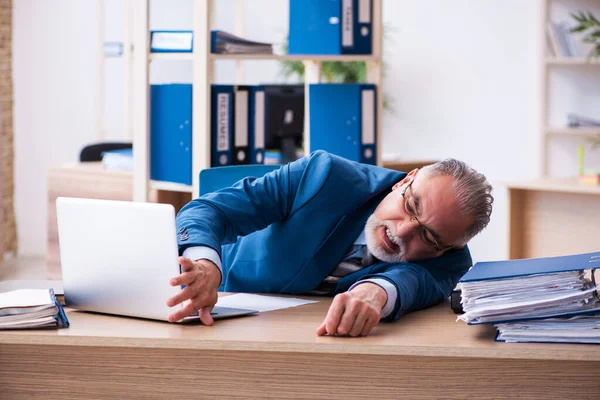 Oude mannelijke boekhouder ongelukkig met buitensporig werk op de werkplek — Stockfoto