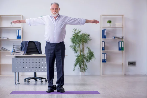 Empleado varón envejecido haciendo ejercicios físicos durante el descanso — Foto de Stock