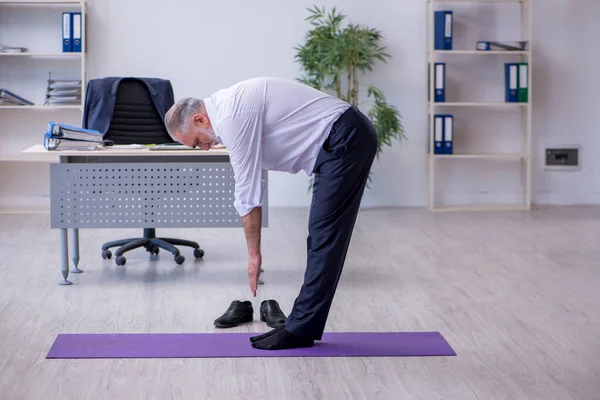 Ältere männliche Mitarbeiter machen in der Pause körperliche Übungen — Stockfoto