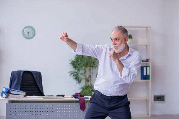 Ältere männliche Mitarbeiter machen in der Pause körperliche Übungen — Stockfoto