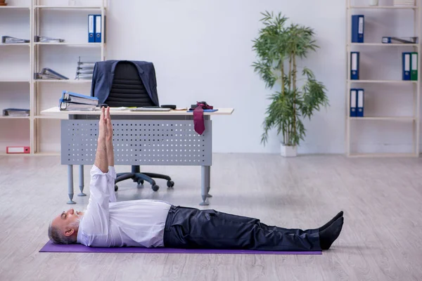 Employé masculin âgé faisant des exercices physiques pendant la pause — Photo