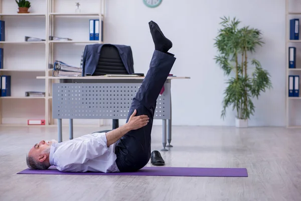 Empleado varón envejecido haciendo ejercicios físicos durante el descanso — Foto de Stock