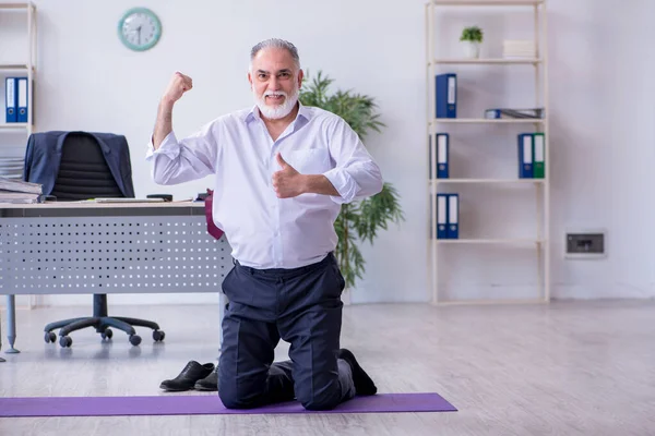 Empleado varón envejecido haciendo ejercicios físicos durante el descanso — Foto de Stock