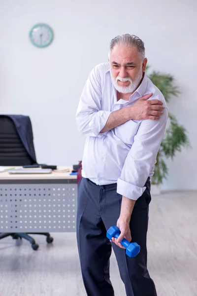 Věk muž zaměstnanec dělá fyzické cvičení během přestávky — Stock fotografie