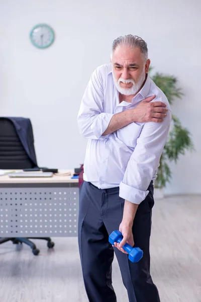 Åldrad manlig anställd som motionerar under pausen — Stockfoto