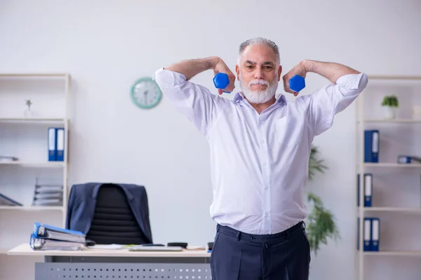 Empleado varón envejecido haciendo ejercicios físicos durante el descanso —  Fotos de Stock