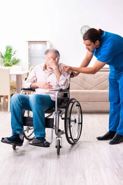 Oude man in rolstoel en jonge slechte verzorger binnen — Stockfoto