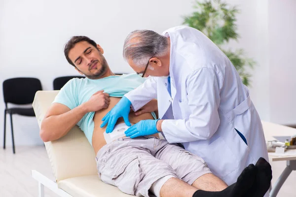 Injured young man visiting experienced male doctor — Stockfoto