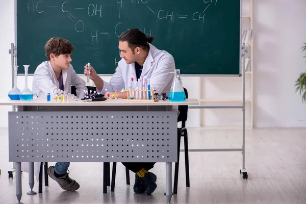 Young chemistry teacher and schoolboy in the classroom — Stock Photo, Image