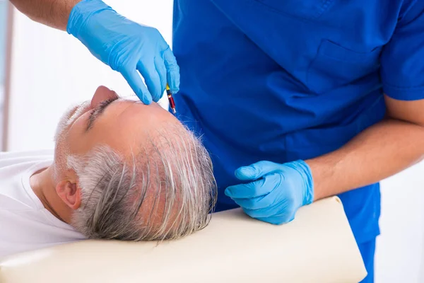 Vieil homme visitant jeune médecin masculin en conce de transplantation de cheveux — Photo