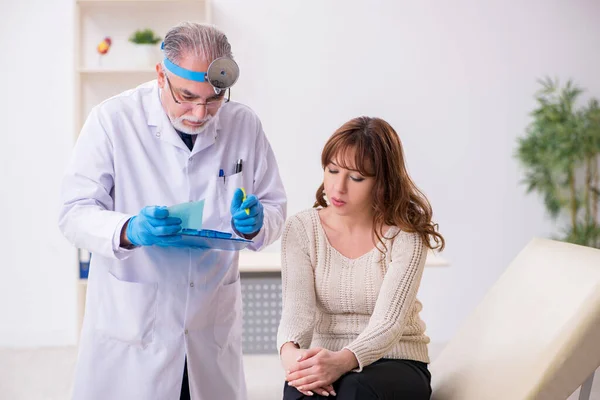 Giovane donna in visita vecchio medico maschio otorinolaringoiatra — Foto Stock