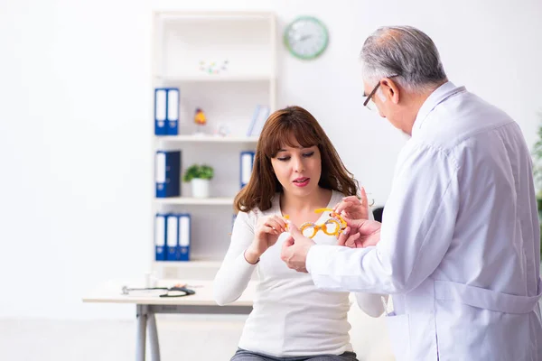 Jovem mulher visitando velho médico oftalmologista masculino — Fotografia de Stock