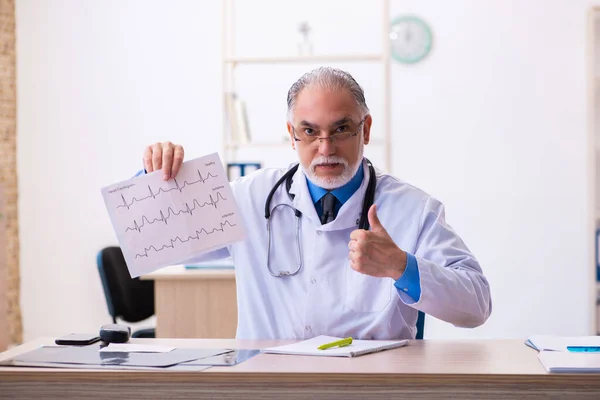 Starý lékař kardiolog vypadá elektrokardiogram — Stock fotografie
