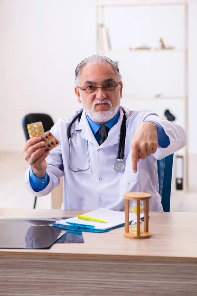Viejo médico de sexo masculino escribiendo prescripción en la clínica —  Fotos de Stock