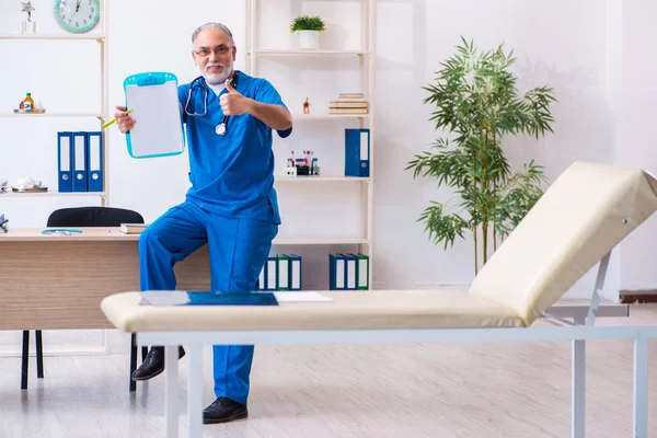 Gammal manlig läkare antecknar på kliniken — Stockfoto