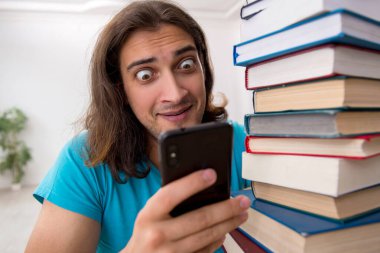 Genç bir erkek öğrenci ve sınıfta bir sürü kitap var.