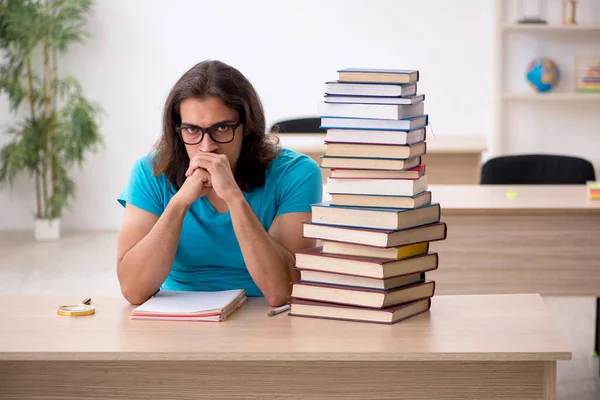 Giovane studente maschio e un sacco di libri in classe — Foto Stock