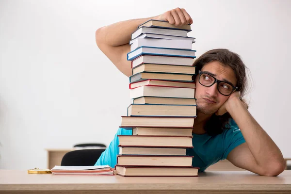 Giovane studente maschio e un sacco di libri in classe — Foto Stock