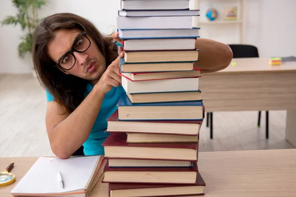 Jeune étudiant masculin et beaucoup de livres dans la classe — Photo